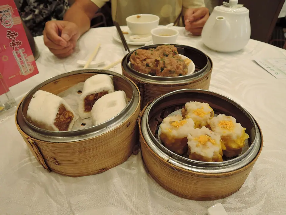 Bamboo steamers filled with dim sum and teapots on a restaurant table