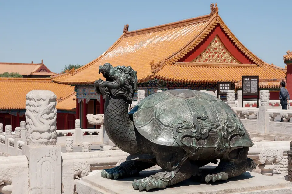Bronze tortoise in a courtyard beneath red walls and golden roofs in Beijing’s Forbidden City
