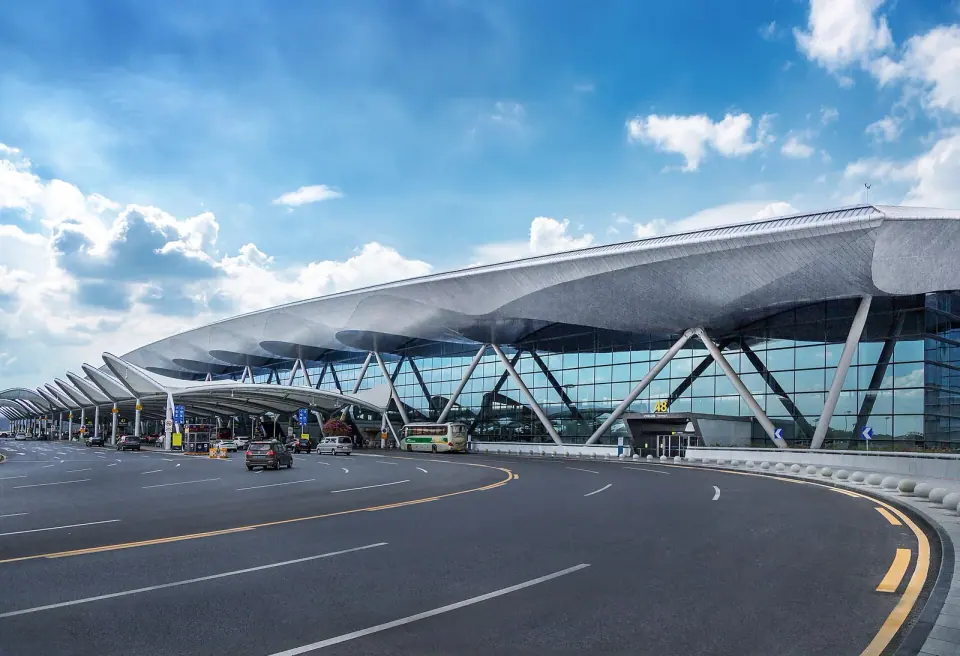 Roadside view of the glass facade and sweeping roof of Guangzhou Baiyun Airport Terminal 2
