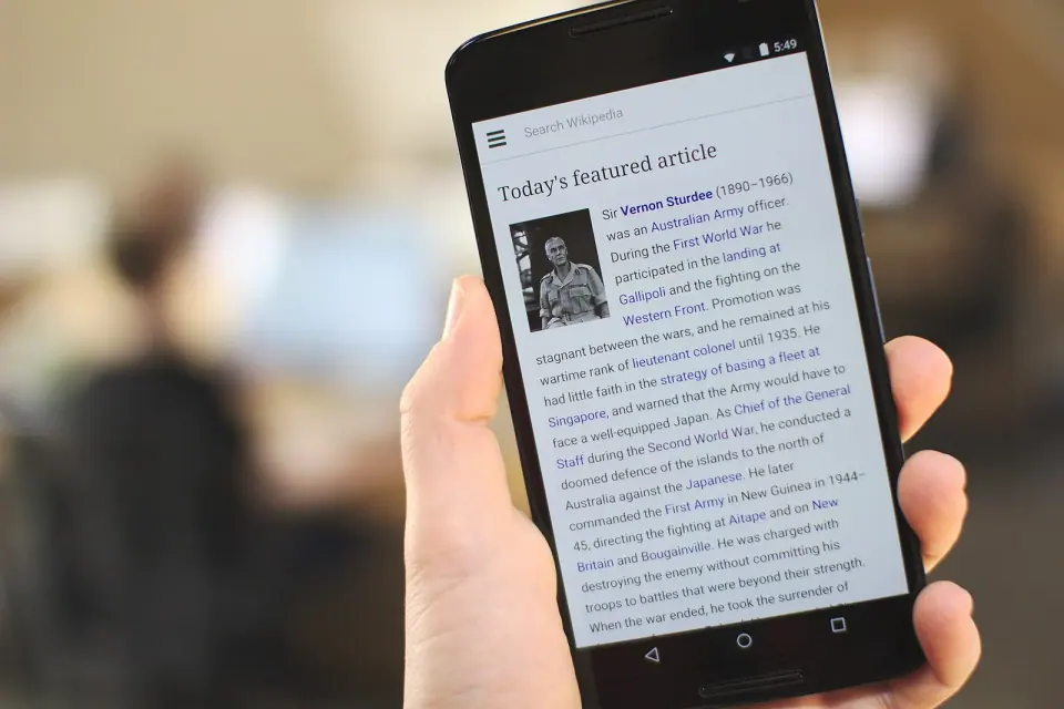 Hand holding an Android smartphone with an article displayed on its screen