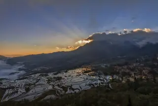 Water-filled Yuanyang rice terraces reflecting the sunrise beneath mountain ridges